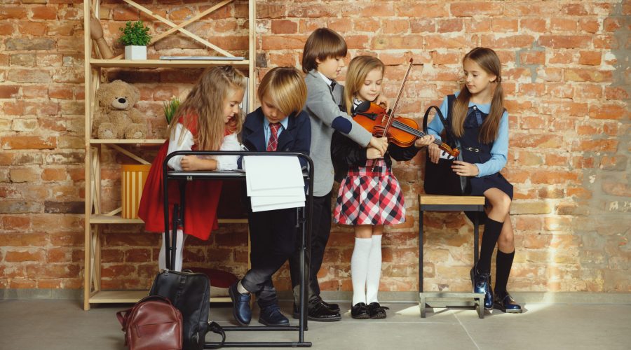 Group of kids spending time after school together. Handsome friends resting after classes before start of doing homework. Modern loft interior. Schooltime, friendship, education, togetherness concept.
